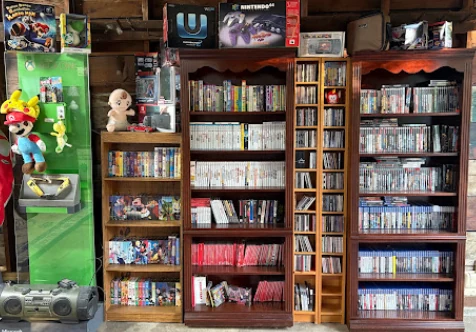 Wall of bookcases filled with games, boxed consoles, and collectibles